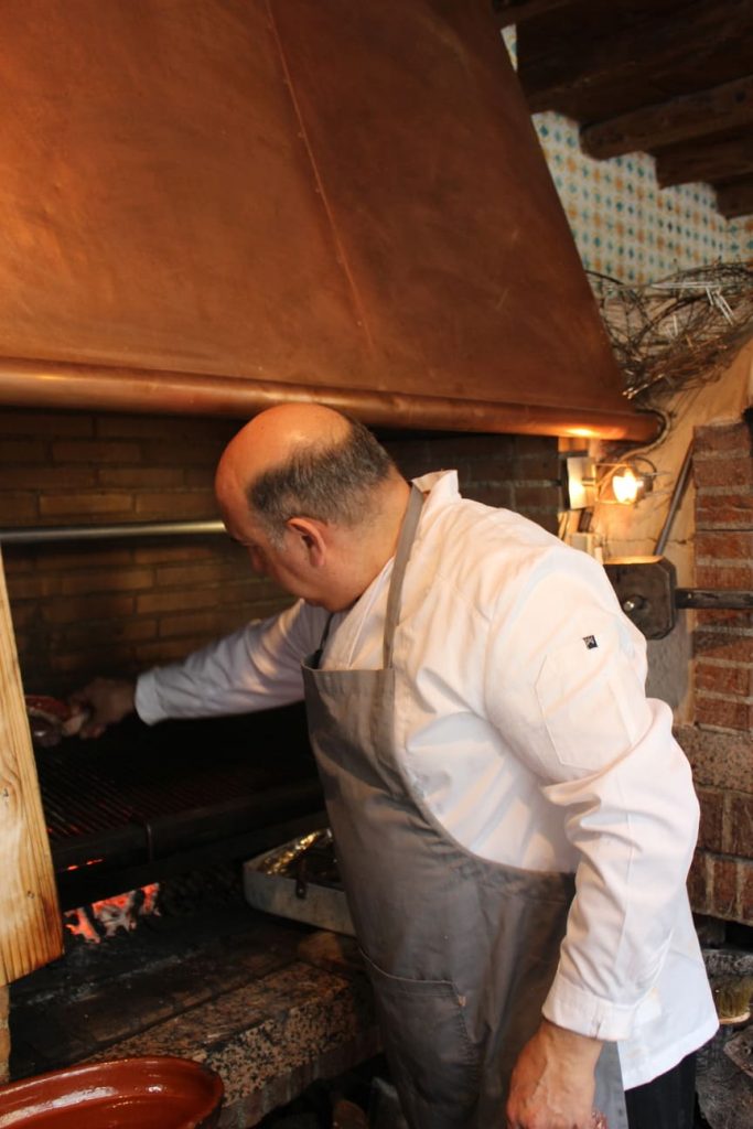 Cocinero preparando carne en la parrilla en nuestro restaurante en Madrid.