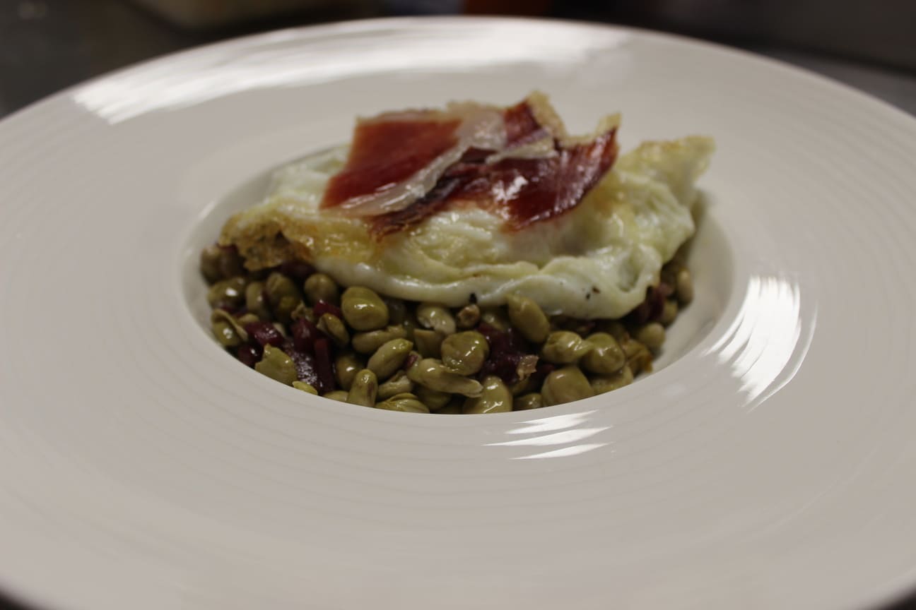 Delicioso plato de habas con jamón, un plato típico y sabroso de nuestro restaurante en Madrid.